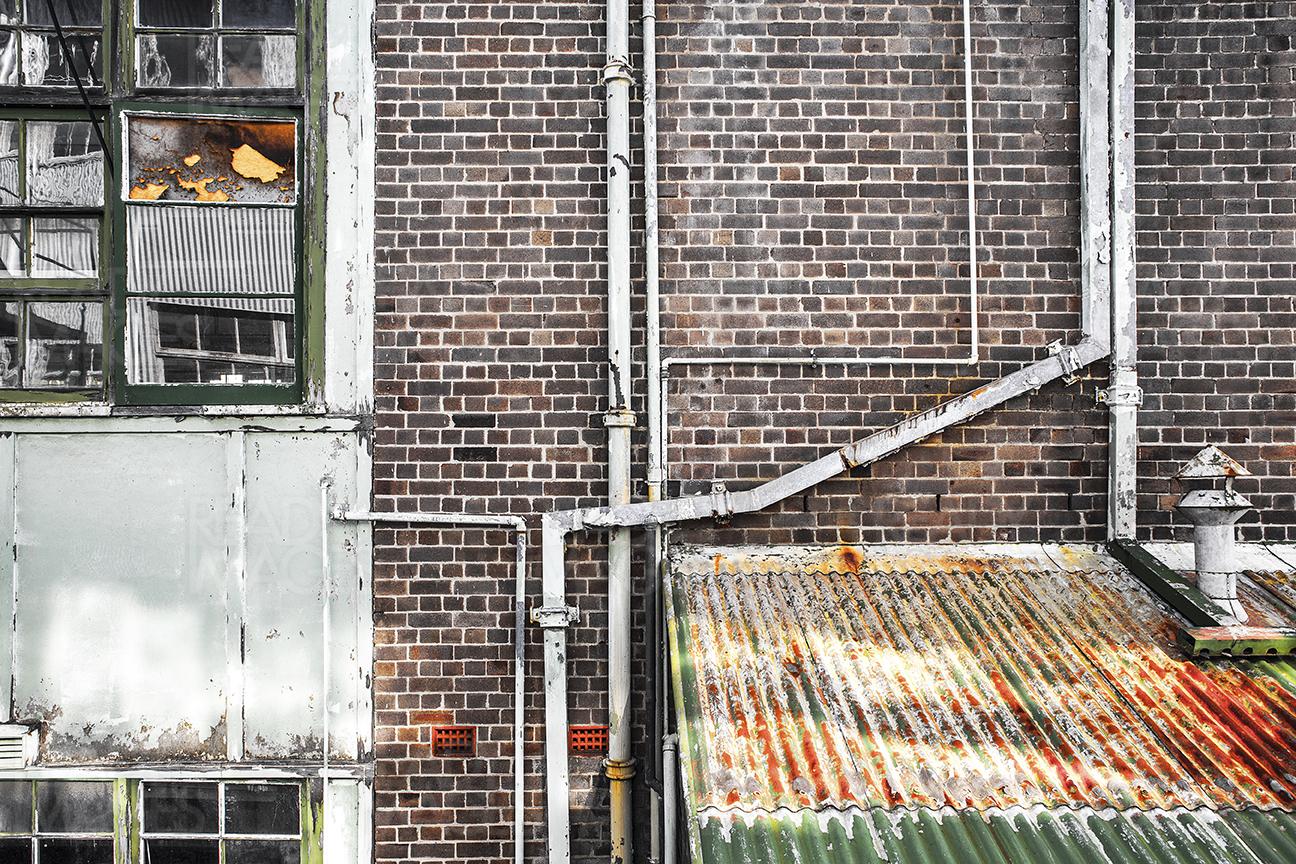 Old weathered Facade showing a textured brick wall, dilapidated windows and rusty, corrugated awning. Image is from Ship Design Prescient of Cockatoo Island, Sydney, Australia