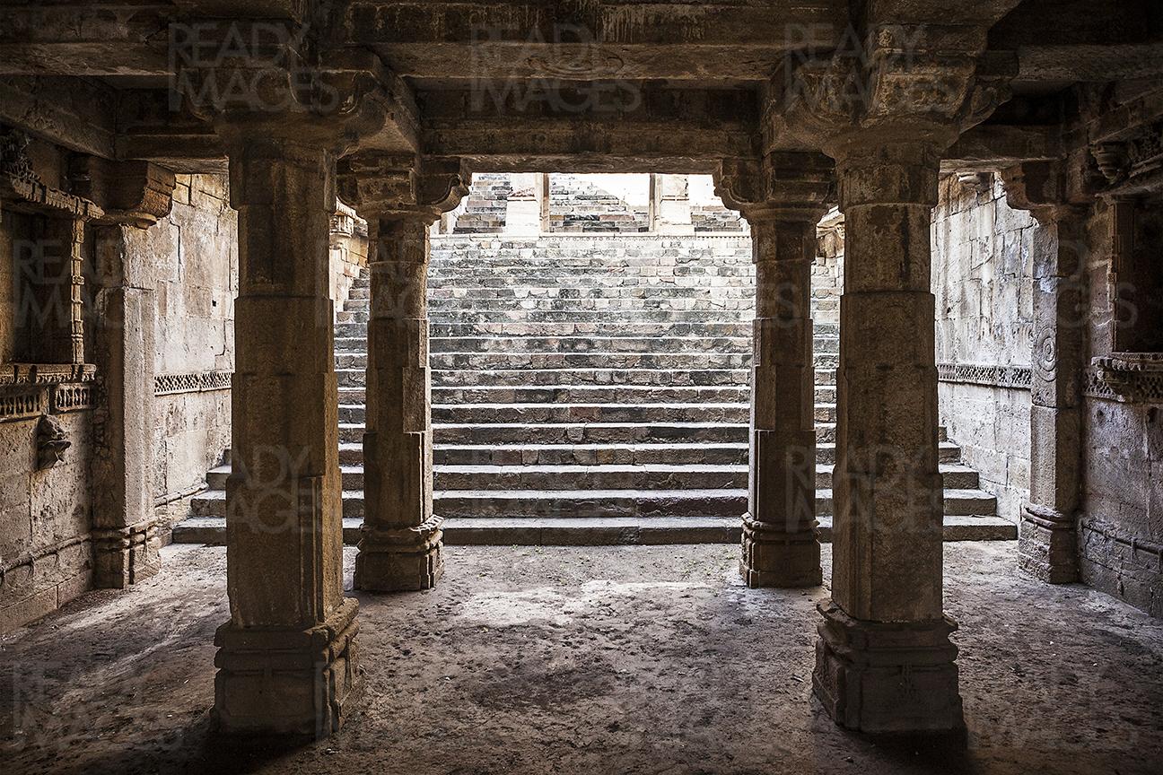 Symmetrical image from the centre of the Jethabhai Stepwell looking towards an arched colonnade and steps near the entry, Ahmedabad, India