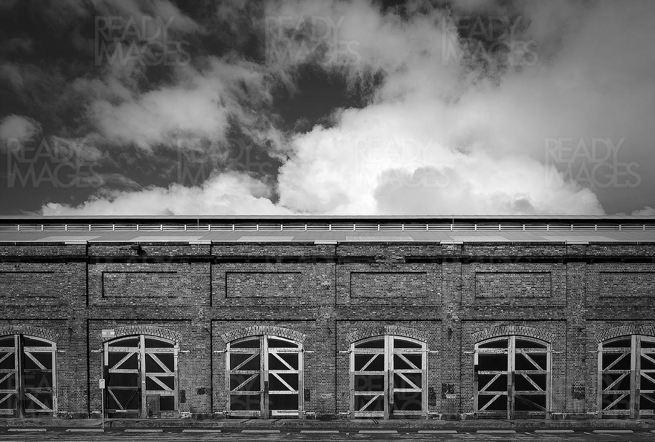 Black and white fine art image of the Carrigeworks, old train sheds converted into the multi-arts urban cultural precinct and dramatic cloud formation in the background