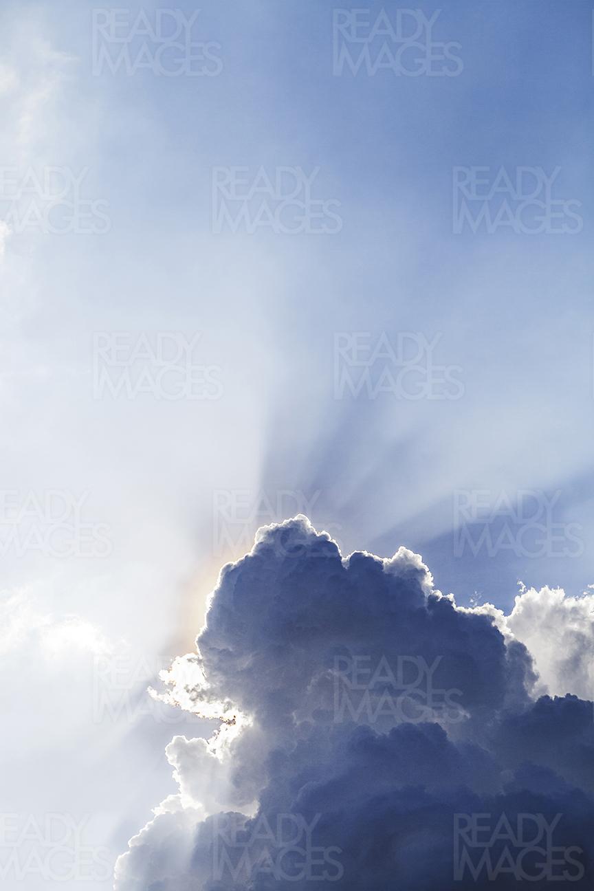 Image of the sun hidden behind a thick black cloud with silver lining on a bright summer day