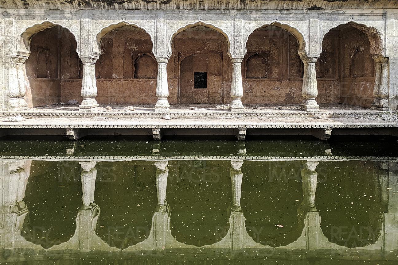 Symmetrical image of an arched colonnade with water reflection