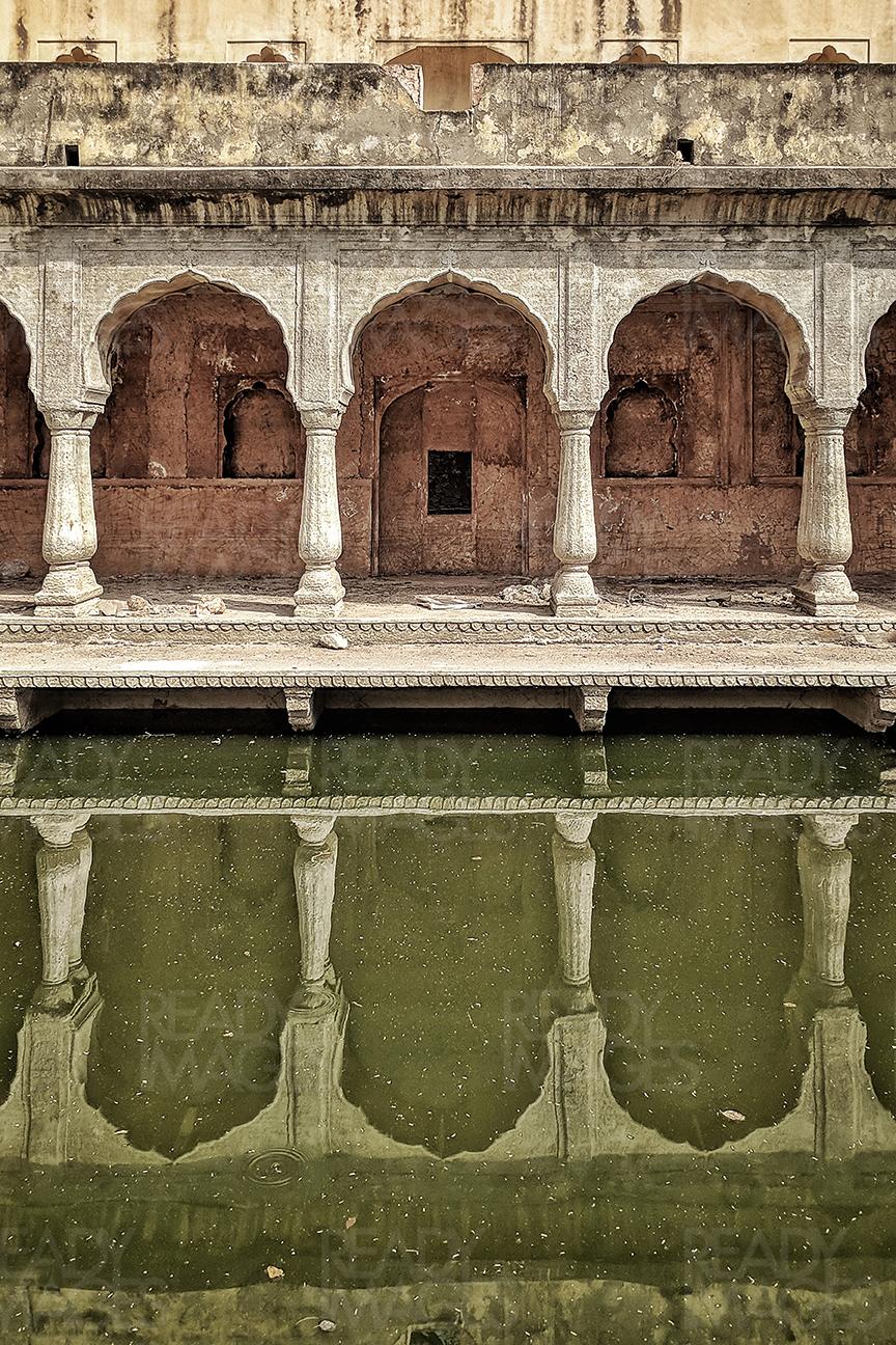 Symmetrical image of an arched colonnade with water reflection