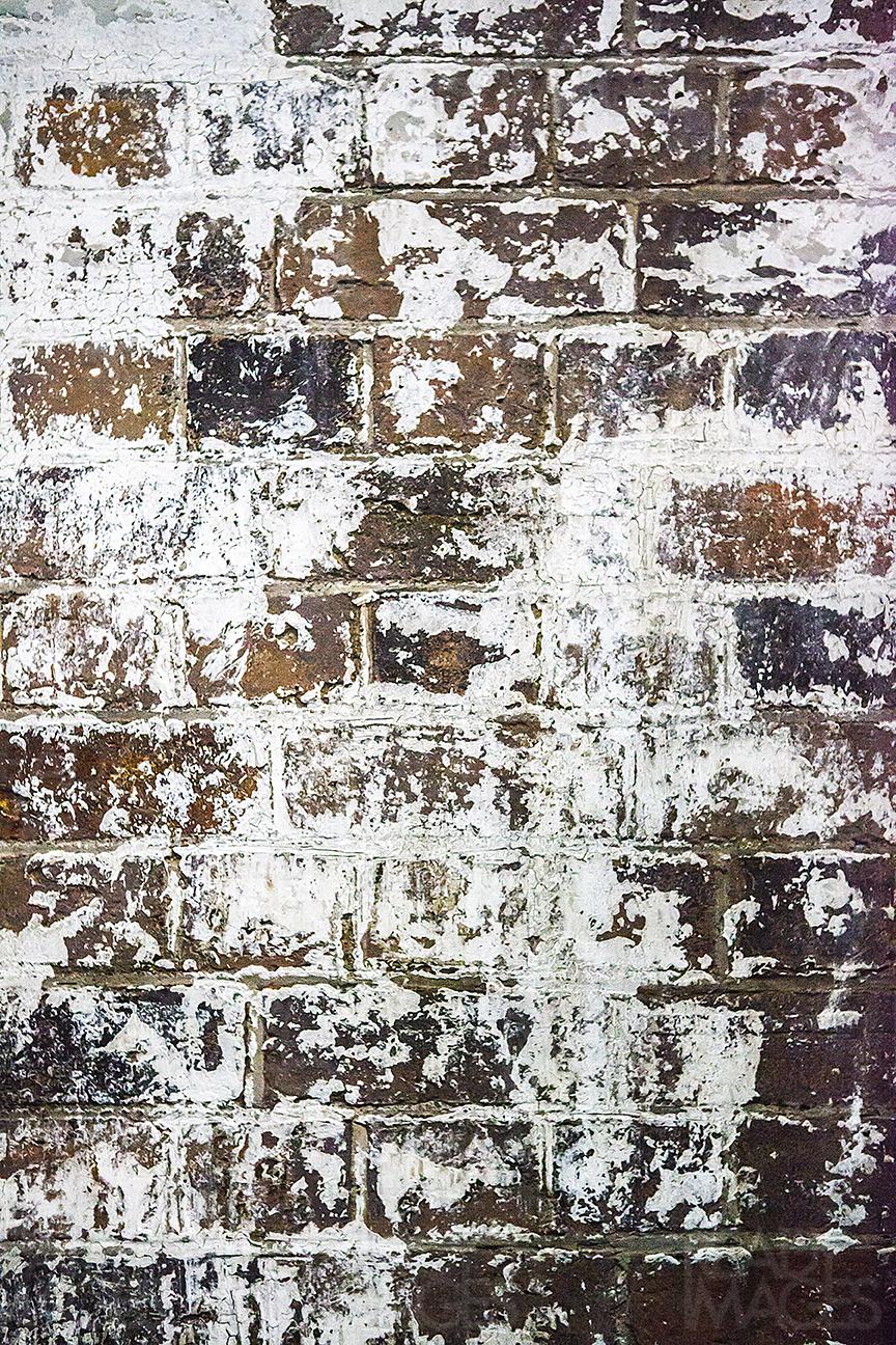 Image of an old damaged brick wall, with peeled white paint marks
