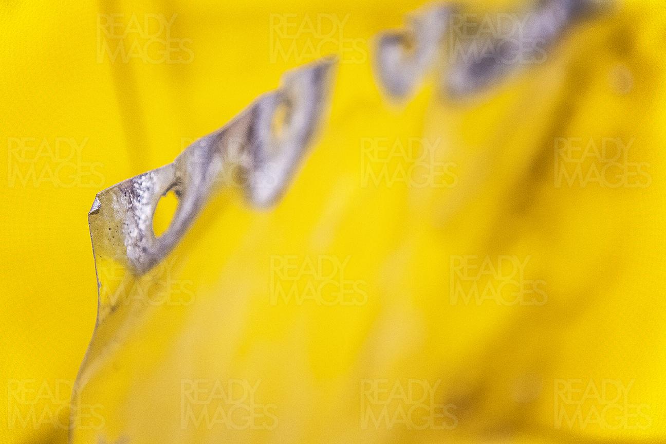 Close-up abstract image of shiny yellow paint on an old metal sheet with holes