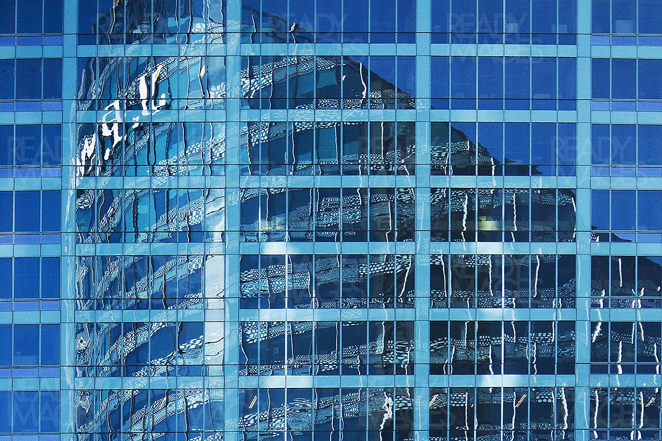 A blue glass curtain wall reflecting adjacent tall commercial building in Sydney CBD