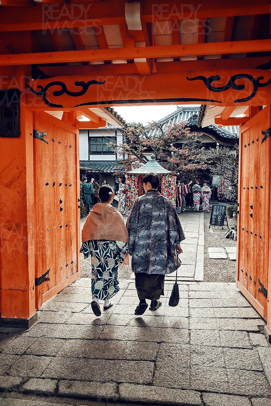 Tourists dressed in traditional Japanese kimonos walking through an orange gate