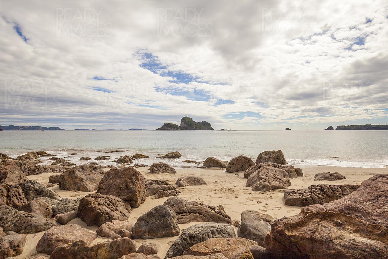 Clouds, rocks, and water at a beach in the Coromandel, New Zealand