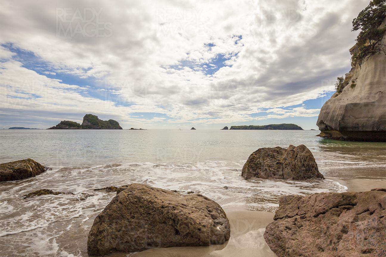 Clouds, rocks, and water at a beach in the Coromandel, New Zealand